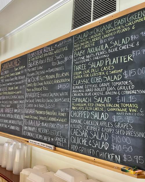 Chalkboard menu featuring sandwiches, salads, and prices, including lobster roll, salads, and quiche options.