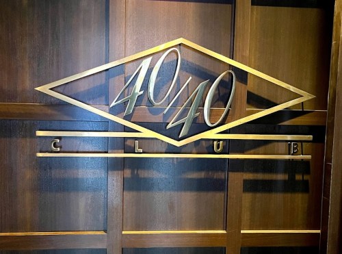Sign for the 40/40 Club, featuring a gold and wood design with the club's name prominently displayed.