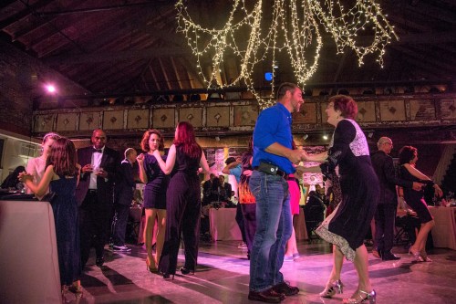 A lively dance floor with people in formal attire enjoying a celebration under twinkling lights.