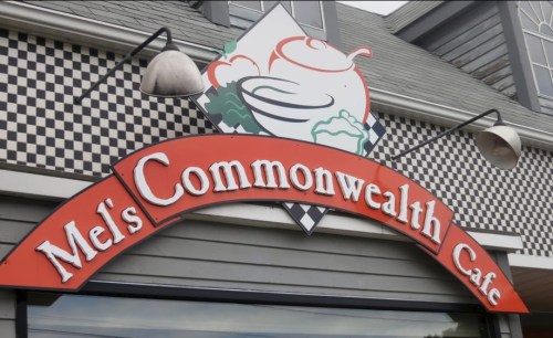 Sign for Mel's Commonwealth Cafe featuring a logo with a bowl and decorative elements.