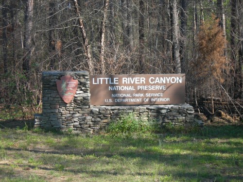 Sign for Little River Canyon National Preserve, featuring stone base and surrounded by trees in a natural setting.