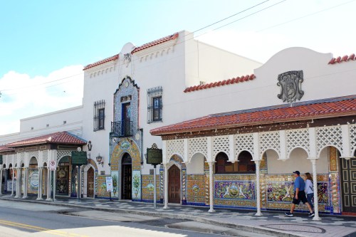Colorful tiled building with ornate architecture and arched doorways, set along a sunny street.