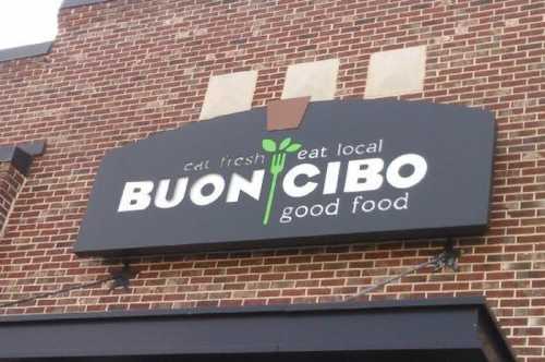 Sign for "Buon Cibo" featuring the tagline "Eat fresh, eat local, good food" on a brick building.