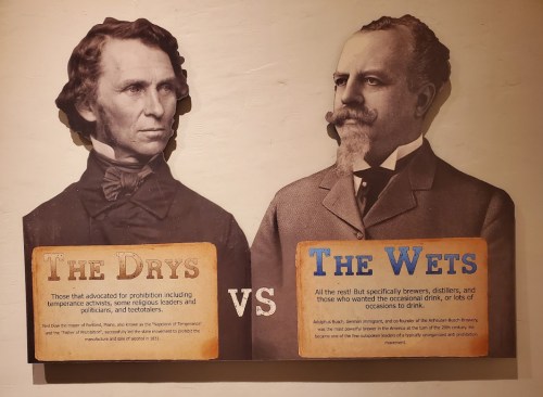Sign comparing "The Dry" advocates for prohibition and "The Wet" supporters of alcohol consumption, featuring two historical figures.