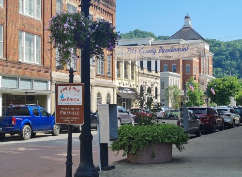 A street view of Pikeville, Kentucky, featuring a welcome sign and historic buildings with a bicentennial banner.
