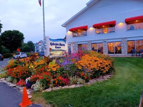 A resort building with red awnings, surrounded by vibrant flower beds and a well-maintained lawn.