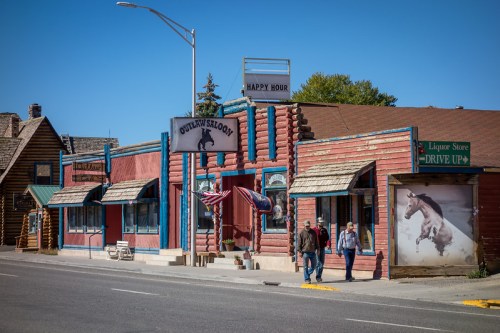 A colorful western-style building with a sign for "Outlaw Saloon" and a liquor store, set against a clear blue sky.