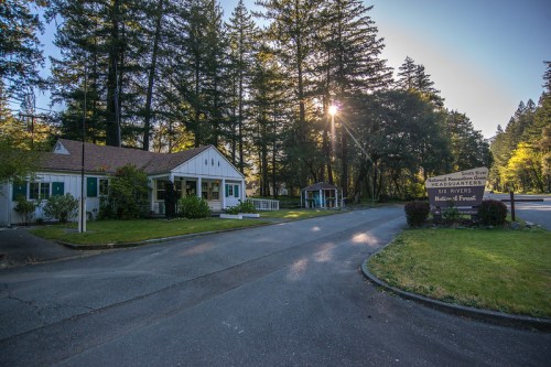 A scenic view of a building surrounded by trees, with a sign reading "Headquarters of the Rivers" and sunlight peeking through.