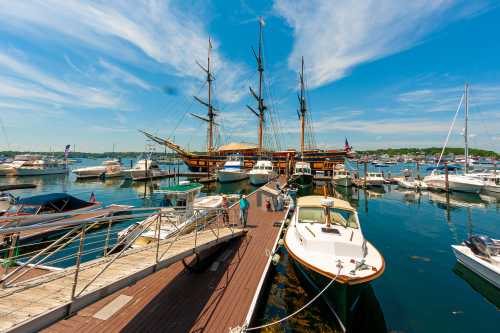 A vibrant marina scene with a tall ship and various boats docked under a clear blue sky.