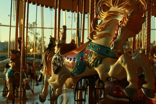 A colorful carousel with ornate horses, illuminated by warm sunlight, creating a nostalgic atmosphere.