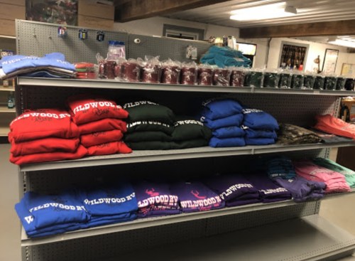 A display of colorful sweatshirts and candles on shelves in a store.