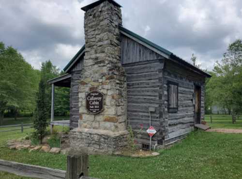 Historic Callaway Cabin, built in 1832, featuring a stone chimney and surrounded by greenery.