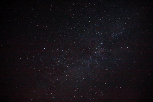 A starry night sky filled with countless stars and a faint hint of the Milky Way galaxy.
