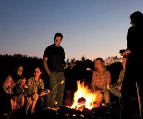 A group of people gathered around a campfire, roasting marshmallows and enjoying the evening outdoors.
