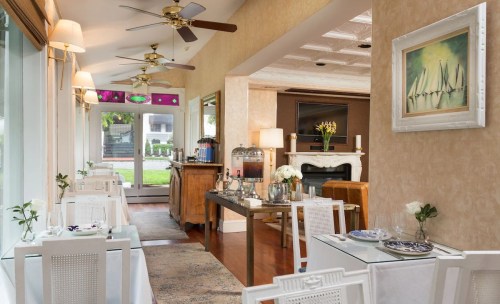 Cozy dining area with white tables, wooden bar, and decorative fans, featuring a warm, inviting atmosphere.