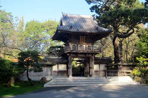 A traditional Japanese gate surrounded by lush greenery and trees in a serene garden setting.