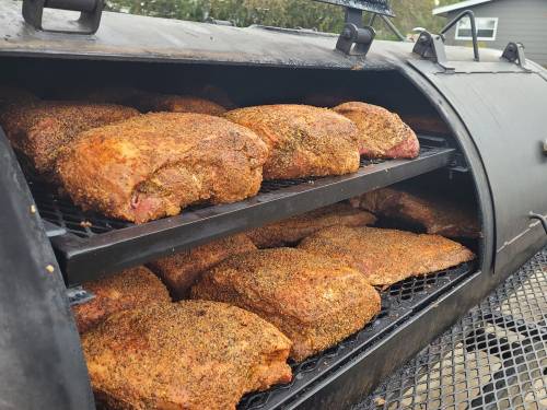 Smoked meats on racks inside a barbecue smoker, seasoned and ready for cooking.