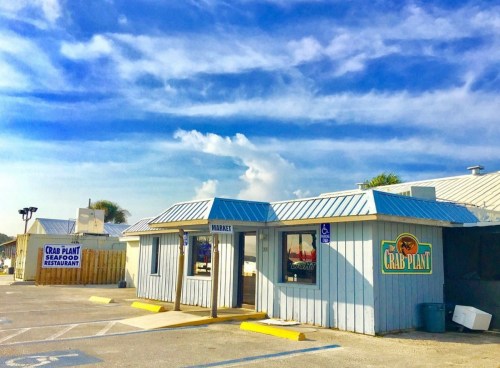 A seafood restaurant called "The Crab Plant" with a blue sky and clouds in the background.
