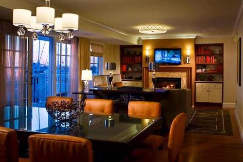 Modern living room with a dining area, elegant lighting, a fireplace, and a TV, featuring warm tones and stylish decor.