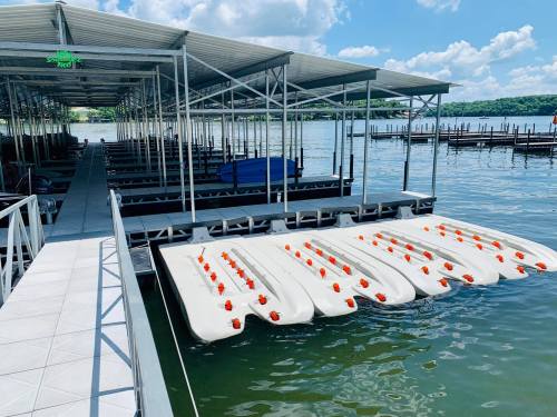 A marina with floating docks and boats on calm water under a blue sky with scattered clouds.