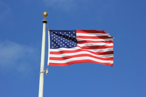 Waving American flag on a flagpole against a clear blue sky.