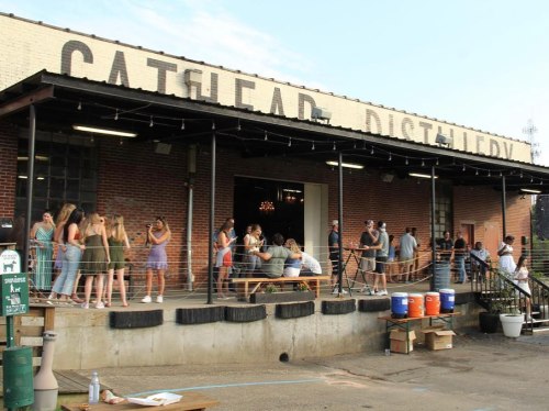 A lively outdoor scene at Cathead Distillery, with people socializing on a patio and enjoying the atmosphere.