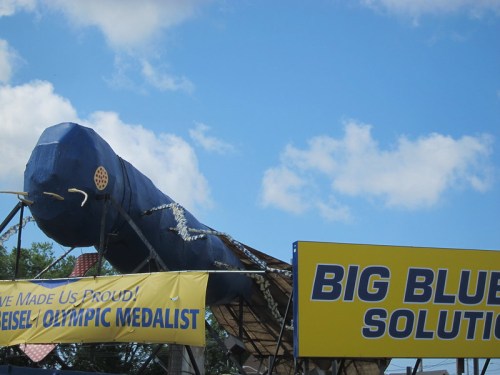 A large blue sculpture resembling a fish or sea creature, with a sign reading "BIG BLUE SOLUTIONS" nearby.