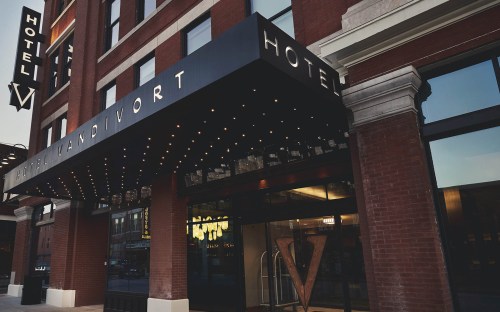 Exterior view of Hotel V, featuring a marquee with lights and a modern entrance.