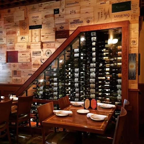 A cozy restaurant interior featuring a wine rack under a staircase, surrounded by wooden wine crate decor.
