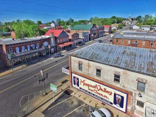 Aerial view of a small town featuring historic buildings, shops, and a prominent ice cream advertisement on a brick wall.