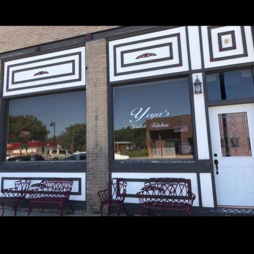 Exterior of Yeya's South Kitchen, featuring large windows, decorative trim, and red benches outside.