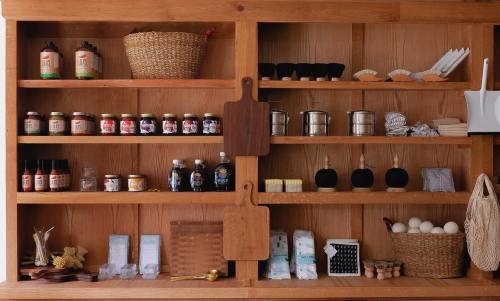 A wooden shelf filled with jars, containers, and baskets, organized neatly with various kitchen items and ingredients.