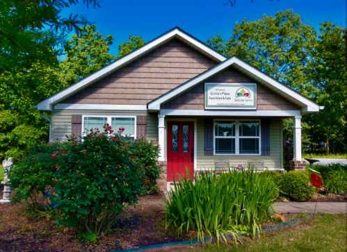 A charming house with a red door, surrounded by greenery and flowers, featuring a sign that reads "Sofia's Place."