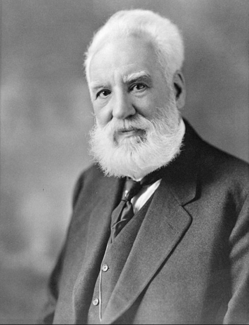 Black and white portrait of a bearded man in a suit, looking directly at the camera with a serious expression.