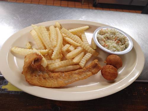 A plate with crinkle-cut fries, a piece of fried fish, coleslaw, and two hushpuppies.