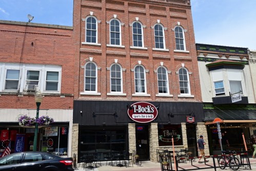 Exterior of T-Bock's Sports Bar & Grill, a brick building with large windows, located in a downtown area.