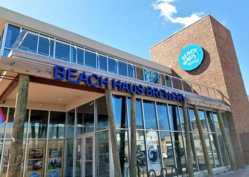 Exterior of Beach Haus Brewery with large signage and a modern design, featuring glass windows and a blue sky.