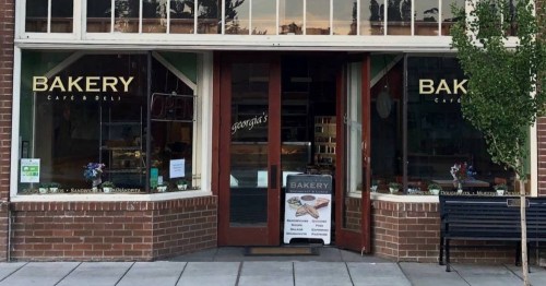 A bakery storefront with large windows, displaying baked goods and a sign that reads "Bakery" and "Georgie's."