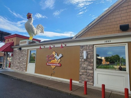 A restaurant exterior featuring a large rooster statue on the roof and a sign that reads "Henny Penny Restaurant & Bar."