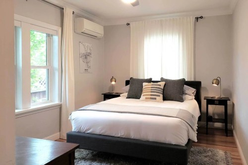 Cozy bedroom with a queen bed, two bedside lamps, and large windows letting in natural light.