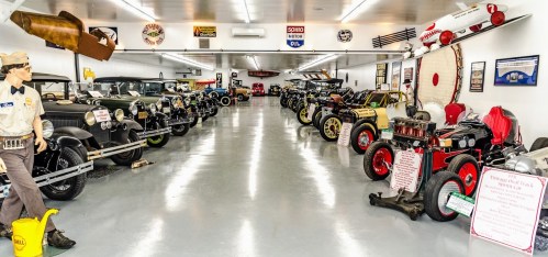 A vintage car museum featuring a variety of classic cars and memorabilia displayed in a spacious, well-lit room.