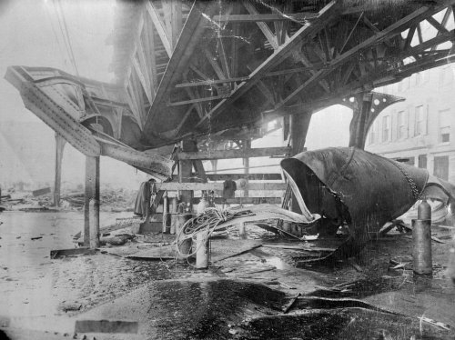 A damaged industrial structure with twisted metal and debris on the ground, depicting a scene of destruction.