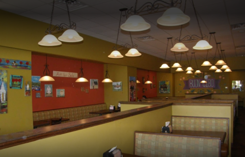 Cozy restaurant interior with warm lighting, colorful artwork on the walls, and booth seating.