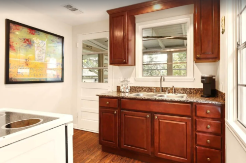 A cozy kitchen featuring wooden cabinets, a granite countertop, and a window with natural light.