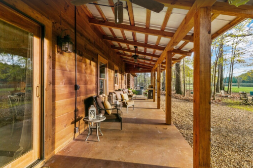 A cozy wooden porch with seating, overlooking a serene outdoor area surrounded by trees.