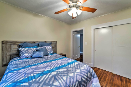 Cozy bedroom featuring a patterned bedspread, ceiling fan, and closet doors in a softly lit space.