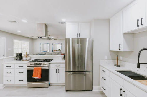 Modern kitchen with stainless steel appliances, white cabinets, and a spacious layout featuring a gas stove and sink.