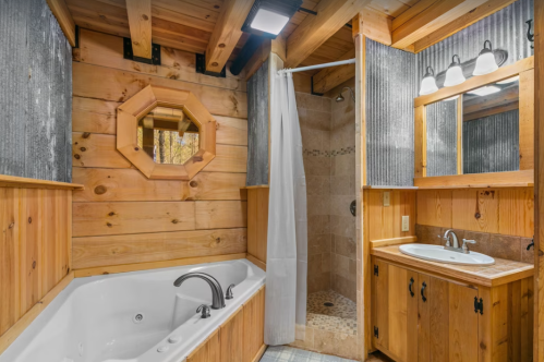 Cozy bathroom featuring a wooden design, a shower, a bathtub, and a mirror with warm lighting.