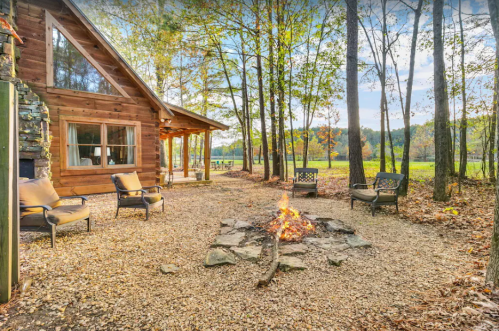 Cozy cabin with a fire pit surrounded by trees and a scenic view of the outdoors.