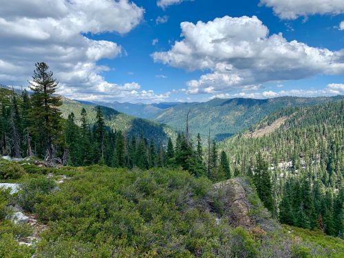A scenic view of a lush green valley surrounded by mountains under a partly cloudy sky.